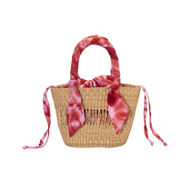 Mini Ayine Woven Bag, natural woven straw tote with red and pink tie-dye fabric handle wrap and drawstring.