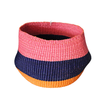 Color Block Bolo Basket in hand-woven grass with pink, navy blue, and orange striped color blocks, round shape.
