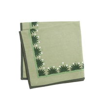 Starburst Napkins in sage green linen fabric with embroidered dark green starbursts and white dots on the border, neatly folded.