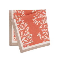 Primrose Napkin | Set of 4, a terracotta fabric napkin with white botanical print and natural beige striped border, neatly folded.