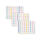 Elisabeth Coated Placemat. Three rectangular white placemats with a vibrant multi-colored grid pattern, stacked diagonally.