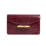 The Jackie wine red embossed crocodile leather flap clutch bag with a gold bamboo clasp on a white background.