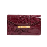 The Jackie wine red embossed crocodile leather flap clutch bag with a gold bamboo clasp on a white background.