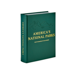 America's National Parks" Book, dark green leather with embossed mountain range and gold foil text, standing on a white surface.