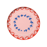 Fête Dinner Plate | Set of 12, round paper plate with pink base, red scalloped border, blue floral wreath, and white dots.